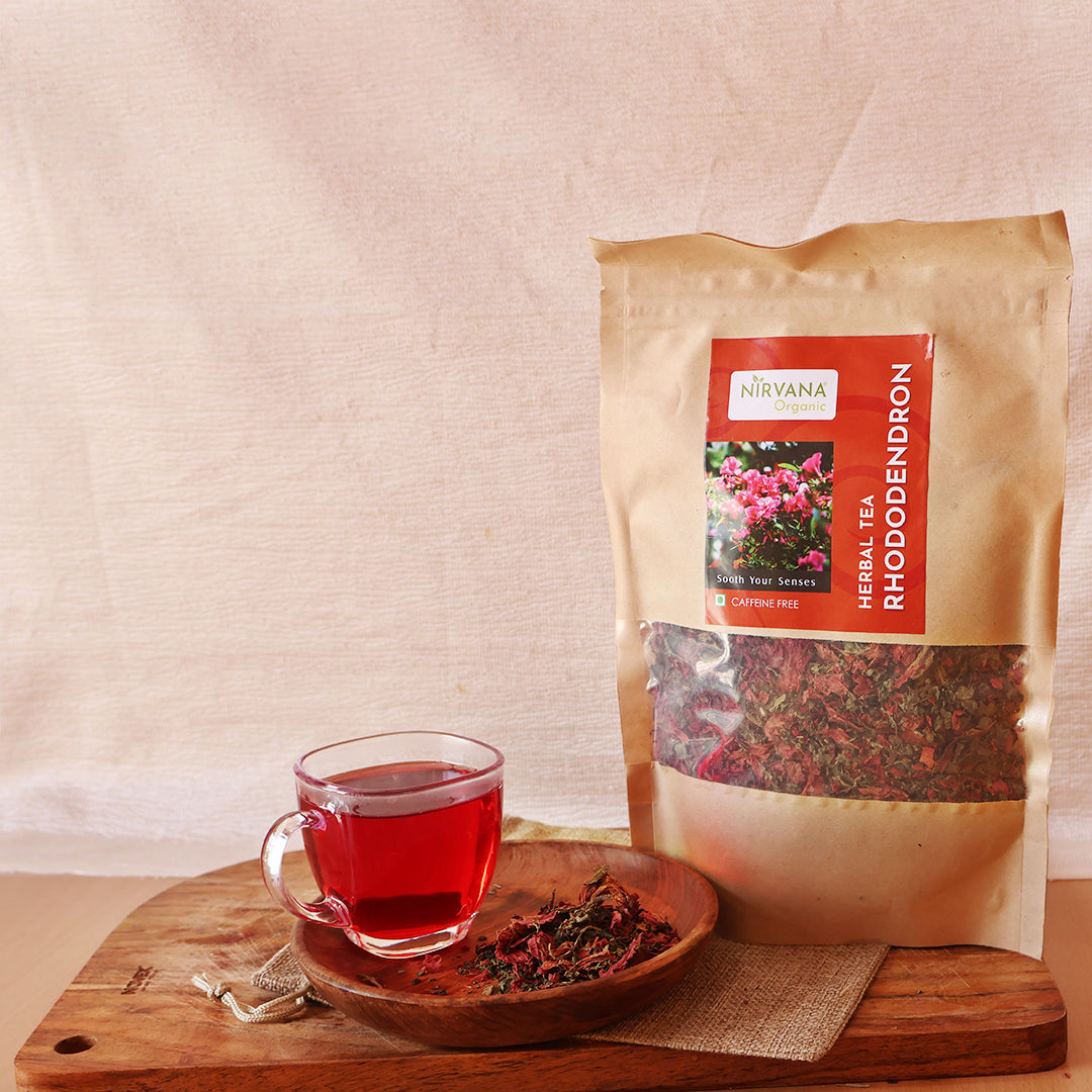 Golden-amber brewed rhododendron tea in clear glass mug with dried flowers - natural anti-aging drink